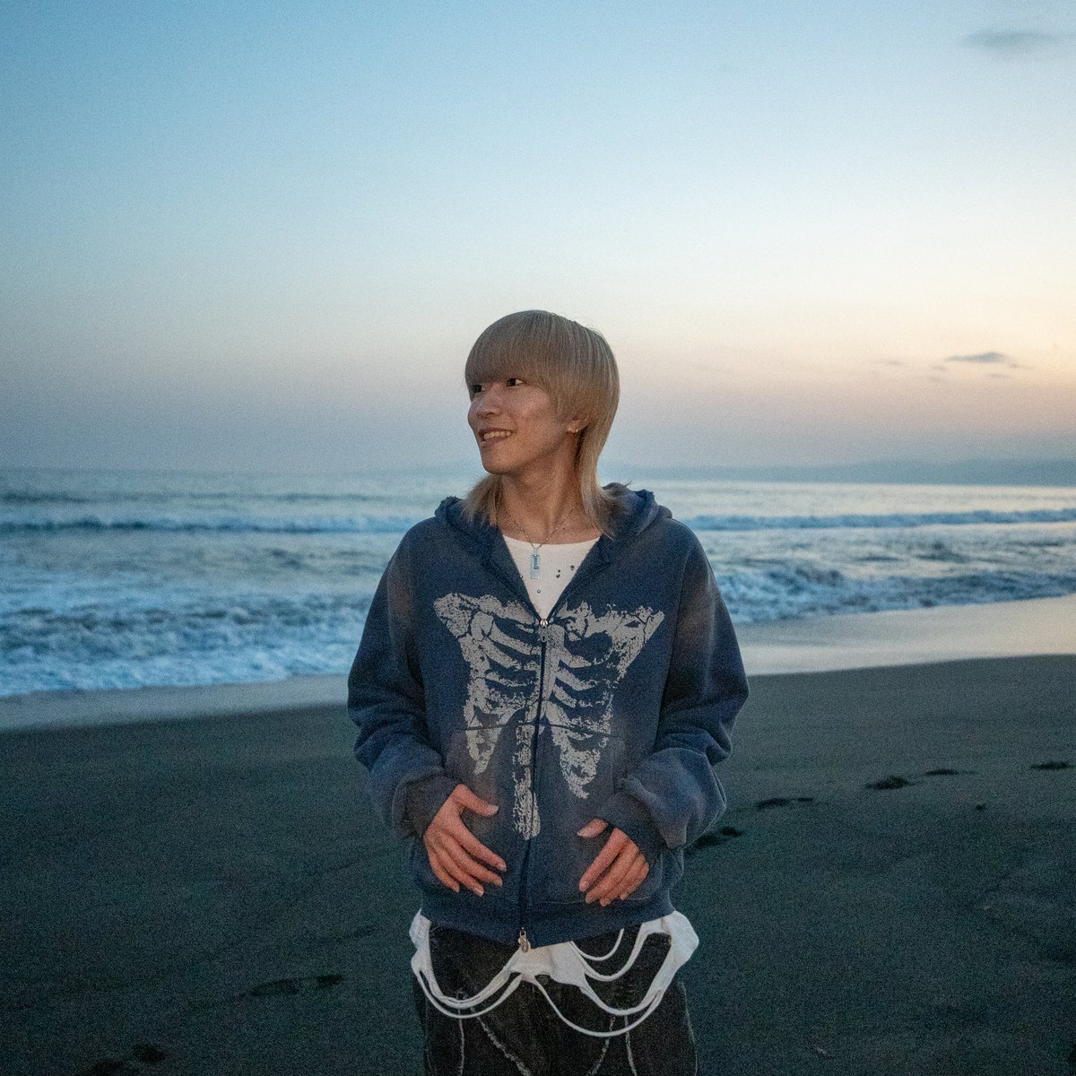 夕方の海辺に立つLITAのアーティスト写真